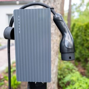Close-up view of electric vehicle charger mounted outdoors in home driveway. Setup reflects commitment to clean energy and convenient personal charging