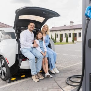 Happy Family Charging Electric Car At Charging Station