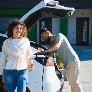 Happy couple charging their electric vehicle at home, showcasing their commitment to sustainable and eco friendly transportation