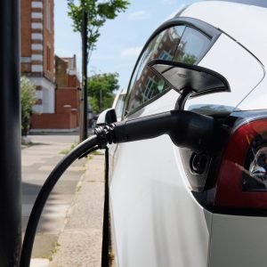 An electric car charges on a sunny day on a London street, embodying modern eco-friendly transportation in an urban setting.